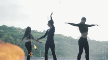 Genç ince adam ve iki güzel kadın aynı anda yol ve ormanın önünde ayakta iken alev ile göstermek gerçekleştirin. Usta fireshow sanatçılar akşam yangın hareket ustaca gösteren