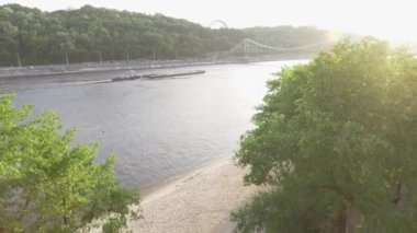 Ukrayna, Kyiv Dnipro Nehri üzerinde güzel peyzaj havadan görünümü. Yeşil ağaçlar, geniş nehir ve köprü. Güneşli parlak bir gün. Drone çekim, üst görünüm