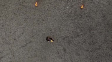 Güvenli ince kadın dans, kum üzerinde ayakta ateş topu ile bir gösteri gerçekleştirme. Usta fireshow sanatçı ateş ve zarif tutkulu dans hareket ustalığını gösteren. Üst görünüm, drone çekim
