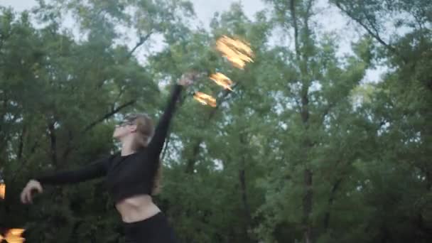Тонкая женщина в маске танцует, выступает с огненным шаром, стоящим на берегу реки. Умелая артистка огненного шоу демонстрирует мастерство движения огня и изящный страстный танец — стоковое видео