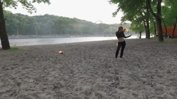 Mujer delgada confiada bailando, realizando un espectáculo con bola de fuego de pie en la arena. Artista de fogata hábil que muestra el dominio del movimiento del fuego y la danza apasionada agraciada. Vista superior, tiro con drones — Vídeo de stock