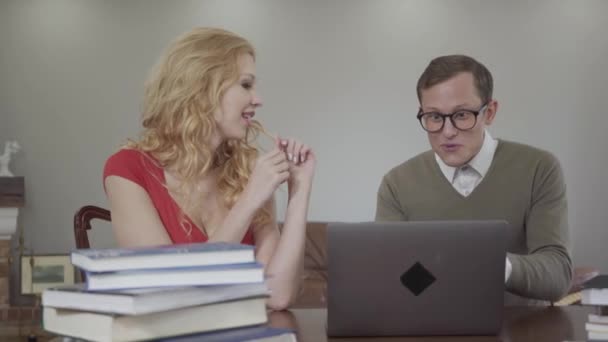 Portret van de student met een bril enthousiast vertelt een verhaal van een mooie verleidelijke meisje. Bescheiden nerd en cute krullend blonde. — Stockvideo