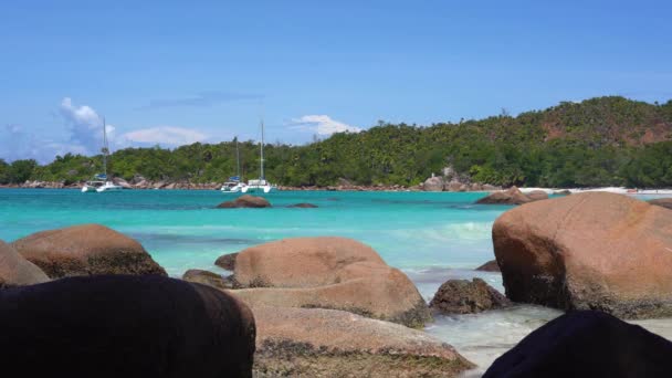 Seychelská. Ostrov Praslin. Nádherný výhled na kamenité pobřeží ostrova, které se nachází v Indickém oceánu. Soukromé jachty v modré mořské vodě na pozadí. Lidé se koupat v moři. — Stock video