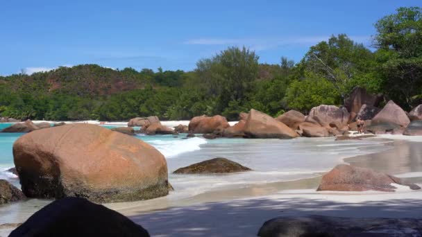 Seychellen. Praslin Island. Schöne Aussicht auf die steinige Küste der Insel im Indischen Ozean. Ein paar Touristen beißen am Strand zu. Menschen baden im Meer. — Stockvideo