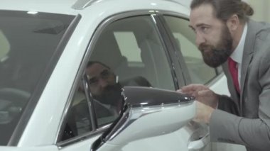 Bir iş elbisenin portre sevimli emin sakallı işadamı yeni otomobil Bayilik satın otomatik inceler. Araba showroom. Reklam konsepti.