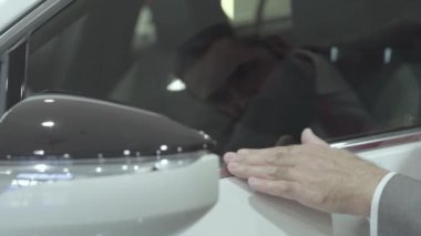 Bir iş elbisenin içinde portre yakışıklı emin sakallı adam yeni araba bayilik satın otomatik inceler. Araba showroom. Reklam konsepti.