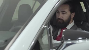 Yeni aracın yolcu bölmesinde oturan portre başarılı sakallı adam Bayilik yeni satın Auto iç inceler. Araba showroom. Reklam konsepti.