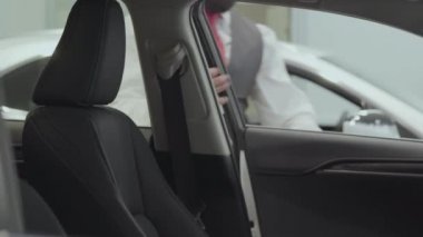 Portre çekici kendine güvenen sakallı işadamı araç oturur ve yeni otomobil Bayilik satın otomatik inceler. Araba showroom. Reklam konsepti.