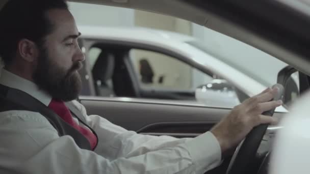 Ritratto attraente uomo d'affari barbuto di successo seduto nel veicolo e ispeziona auto appena acquistata dalla concessionaria auto. Lo showroom dell'auto. Concetto pubblicitario . — Video Stock