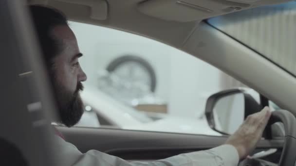 Portret aantrekkelijke vertrouwen baard zakenman zitten in het voertuig en inspecteert nieuw aangekochte auto van de auto dealer. Auto showroom. Reclameconcept. — Stockvideo