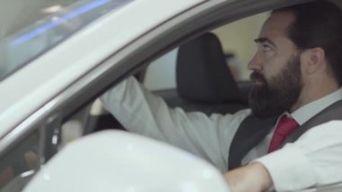 Araç içinde oturan portre çekici emin sakallı işadamı ve araba bayisinden yeni satın otomatik inceler. Araba showroom. Reklam konsepti.