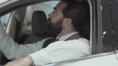 Araç içinde oturan portre çekici emin sakallı işadamı ve araba bayisinden yeni satın otomatik inceler. Araba showroom. Reklam konsepti.