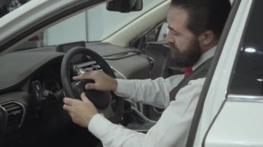 Araç içinde oturan portre çekici emin sakallı işadamı ve araba bayisinden yeni satın otomatik inceler. Araba showroom. Reklam konsepti.
