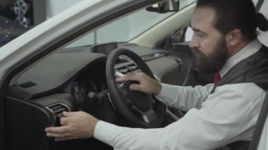 Araç içinde oturan portre çekici emin sakallı işadamı ve araba bayisinden yeni satın otomatik inceler. Araba showroom. Reklam konsepti.