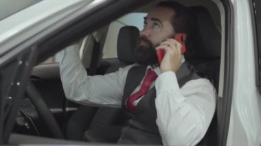 Araç içinde oturan portre çekici emin sakallı işadamı ve araba bayisinden yeni satın otomatik inceler. Bir arabada otururken başarılı adam cep telefonu konuşuyor.