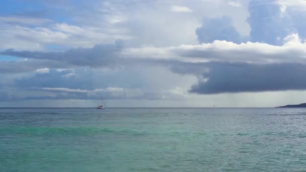 Seychelles. Praslin-sziget. Csodálatos kilátás, tiszta, kék víz és ég. Magányos vitorlás messze az óceánban. Esős felhők lógnak az óceán felszínén. Turizmus, utazás koncepció. Lassított mozgás. — Stock videók