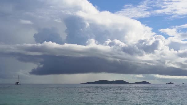 Seicheles. Ilha Praslin. Marina incrível com água azul clara e céu. Veleiro solitário, longe do oceano. Nuvens chuvosas pairam sobre a superfície do oceano. Turismo, conceito de viagem. Movimento lento . — Vídeo de Stock