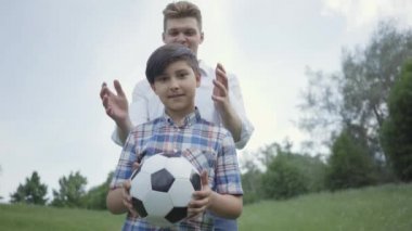 Kameraya bakan sevimli çocuğun portresi, babasının ya da ağabeyinin arkadan gözlerini kapadığı. Çocuk mutlu bir şekilde gülümsüyor. Aile eğlencesi açık havada. Baba ve bir çocuk dışarıda vakit geçiriyorlar.