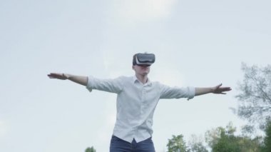 Sanal gerçeklik kulaklık takan adam, gerçekçi görüntü zevk parkta bir uçağın uçuş taklit, yan kollarını yayıldı. Fütüristik ve modern teknolojiler. Adam oyun oynuyor