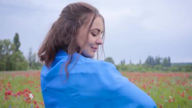 Ukrayna bayrağı ile kaplı bir haşhaş alanında duran güzel kız portresi. Doğayla bağlantı, vatanseverlik. Özgür ruh, duygular, tutku. Doğada boş zaman. Çiçek açan haşhaşlar. Özgürlük.