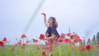 Kulaklık takan sevimli genç kadın müzik dinliyor ve bir haşhaş tarlasında mutlu bir şekilde gülümsüyor. Doğayla bağlantı. Doğada boş zaman. Çiçek açan haşhaşlar. Özgürlük.