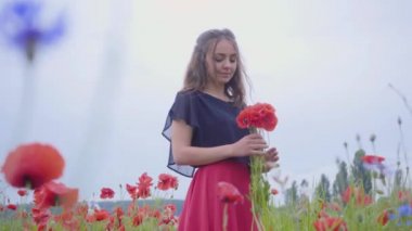 Bir haşhaş tarlasında güzel kız elinde çiçek buketi tutan, güzel çiçekler hayran. Doğayla bağlantı. Yeşil ve kırmızı uyum. Açık havada boş zaman, yaz eğlencesi