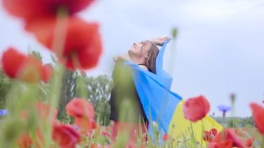 Sevimli sevimli genç kadın elinde açık havada Ukrayna bayrağı tutan bir haşhaş alanında dans. Doğayla bağlantı, vatanseverlik. Doğada boş zaman. Çiçek açan haşhaşlar. Özgürlük.