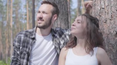 Yakışıklı genç adam ve güzel bir kadının portresi, çam ormanında parmaklarıyla işaret ederek, başka bir yere bakıyor. Vahşi doğayla birlik. Dışarıda dinlenen çift