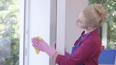 Sevimli genç kadın pencere bez ile pencere temizliği eğlenceli yaşıyor. Ev işleri ve temizlik hizmeti konsepti.