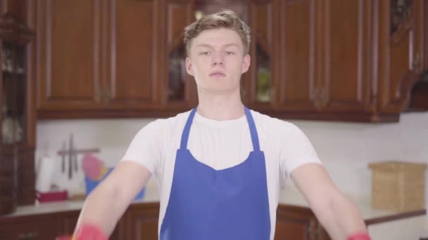 Portrait young cute man raising bottles of detergent up, fooling around. Cleaning day. Housekeeping household housework and cleaning service concept. The concept of advertising. — Stock Video