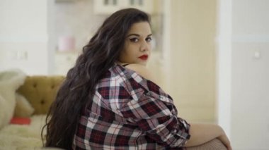 Parlak makyaj ve kırmızı dudaklar flört ile Sevimli tombul güzel kadın, onu oturma odasında omuz baring.