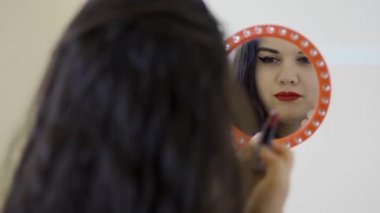 Güzel kendinden emin kadın kırmızı ruj ve flirtily aynada yansıma öpücük ile boyama dudakları makyaj düzeltiyor