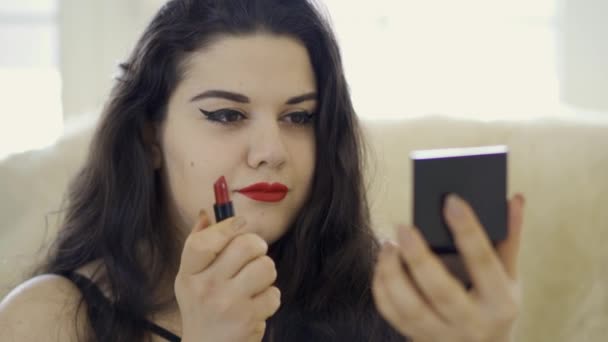 Portrait of pretty overweight girl doing make-up looking in the camera. Plump woman painting her lips with bright red lipstick. Preparing for the date. — Stock Video