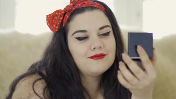 Retrato de atraente jovem plus size menina fazendo make-up olhando no espelho close-up. Mulher gorda se preparando para a data . — Vídeo de Stock