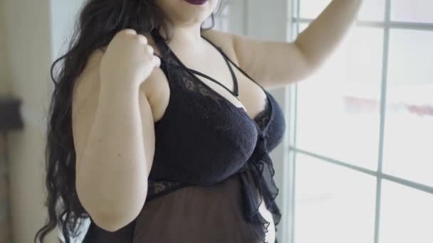 Μποέμ σέξι παχουλός γυναίκα με ορεκτικές σχήματα στέκεται κοντά στο παράθυρο σε όμορφα εσώρουχα και πικάντικο στυλ — Αρχείο Βίντεο