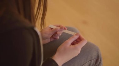 Genç üzgün sinirli kadın iki çizgili bir gebelik testi tutan. İstenmeyen hamilelik. Pozitif gebelik testi. Reşit olmayan bir kız çocuk taşır. Sorunlu gençler