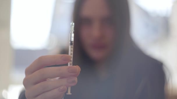 Rozmazaná silueta mladé ženy držící stříkačku s drogou zblízka. Narkoman připravuje injekci injekce heroinu. Znepokojené dospívání. Drogová závislost. — Stock video