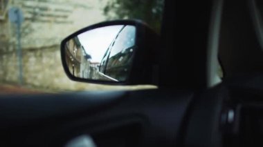 Küçük bir Akdeniz kasabasında sürüş hareket eden bir araba yan aynada yağmurlu akşam sokak yansıması. Seyahat. Kıbrıs.