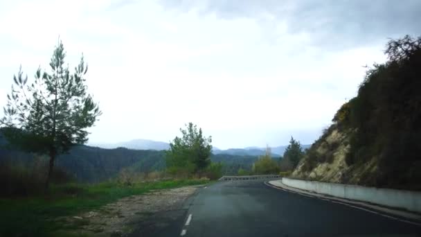Blick aus einem fahrenden Auto auf einer engen Straße mit Häusern, Forellen und Straßenschildern an einem bewölkten Tag nach Regen. Zypern. — Stockvideo