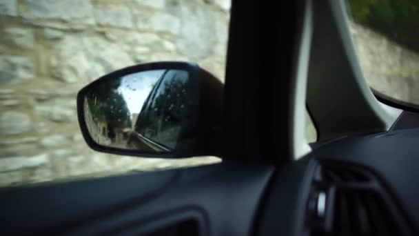 Αντανάκλαση του βροχερούς δρόμου στο πλαϊνό κάτοπτρο ενός μετακινηστού αυτοκινήτου που οδηγεί σε μια μικρή μεσογειακή πόλη. Ταξιδεύουν. Κύπρος. — Αρχείο Βίντεο