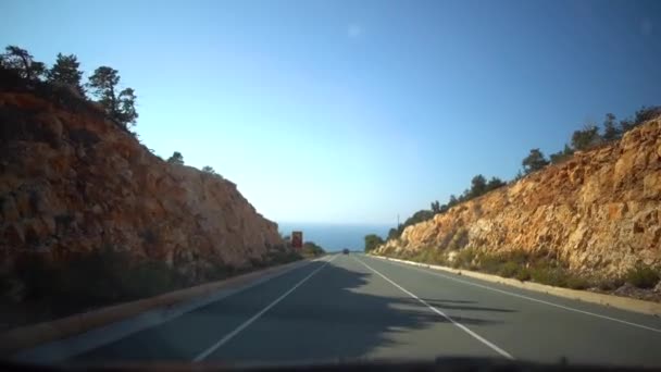 Вид з рухомого автомобіля на вузькій вулиці з будинками, трутами і дорожніх знаків в похмурий день після дощу. Кіпр. — стокове відео