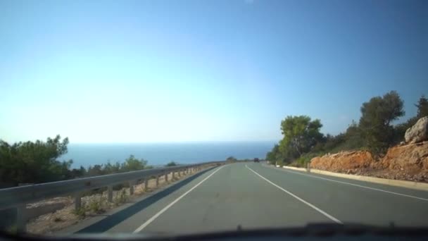 Vista da una macchina in movimento su una strada stretta con case, trote e cartelli stradali in un giorno nuvoloso dopo la pioggia. Cipro . — Video Stock