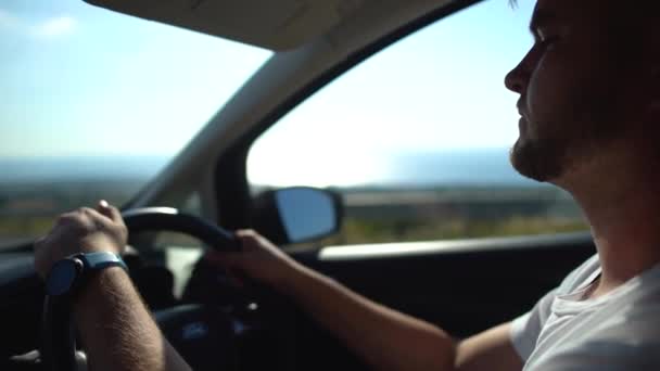 Un joven barbudo conduciendo un auto. Conductor masculino conduciendo un coche con un volante izquierdo en el país con tráfico izquierdo. De cerca. Chipre . — Vídeo de stock