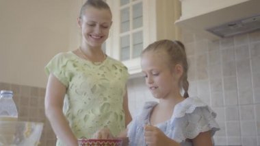Portre genç kadın ve küçük kızı mutfakta evde pasta pişirme. Annelere dokunan kız elleri unla. Anne ve çocuk birlikte vakit geçiriyorlar. Gerçek mutlu aile.