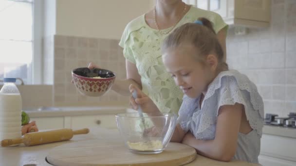 Hübsche junge Mutter und kleine süße Tochter kochen gemeinsam in der Küche. glückliche Familie. Beziehung Mutter und Tochter. — Stockvideo