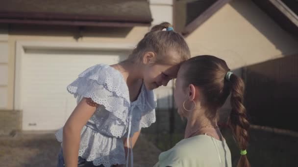 Retrato pequena menina bonito e mãe de pé no quintal ao ar livre. Relacionamento mãe e filha. Família feliz real . — Vídeo de Stock