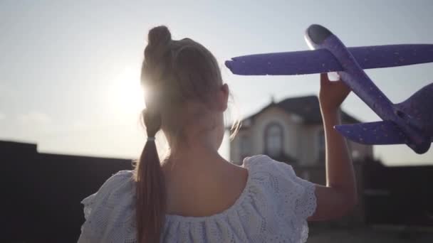 Vista posteriore di una bambina carina che gioca con il piccolo aereo giocattolo primo piano. Il bambino che passa il tempo all'aperto nel cortile. Infanzia spensierata. Rallentatore — Video Stock