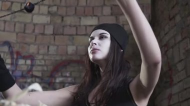 Beyaz yüzlü genç kadın duvarın önündeki terk edilmiş binada yangını söndürdü. Gösteri konsepti. Yangın gösterisi