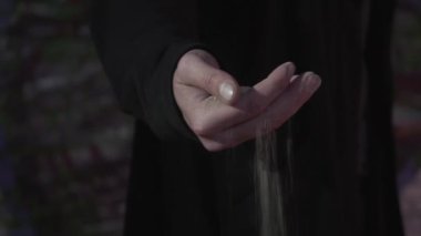 Kum yakın çekimerkek eli. Kum bir adamın parmaklarından akar. Karanlık güzellik konsepti