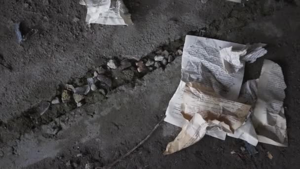 Las páginas de libros arrugadas de cerca yacen en el suelo de hormigón de un edificio abandonado. La copa de vino cae al suelo y se rompe. Concepto de destrucción — Vídeos de Stock